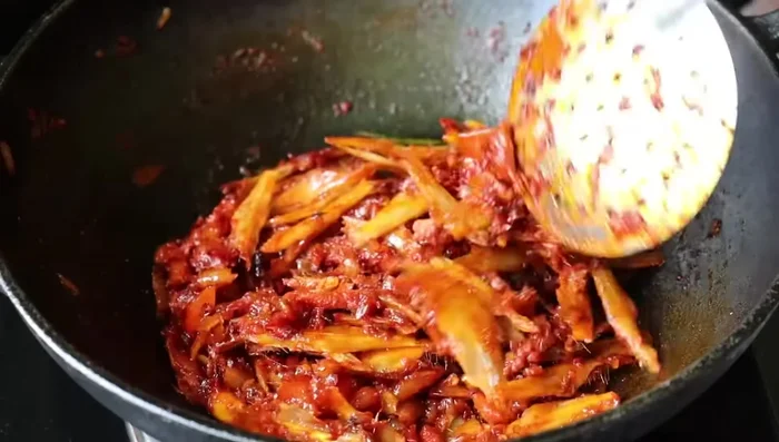 Add the dried anchovies (Nethili Karuvadu). Stir gently to prevent breaking.