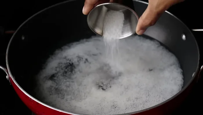 In a pan, combine grated coconut, 2 cups of water, 1 teaspoon of salt, and 2 tablespoons of sugar. Mix well and cook on high flame until it boils. (40.96)