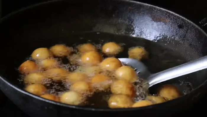 Soak the fried gulab jamuns in syrup. (Music plays during this step)