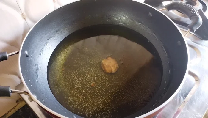 Fry the gulgule until golden brown, stirring occasionally to ensure even cooking. Do not overcrowd the wok.