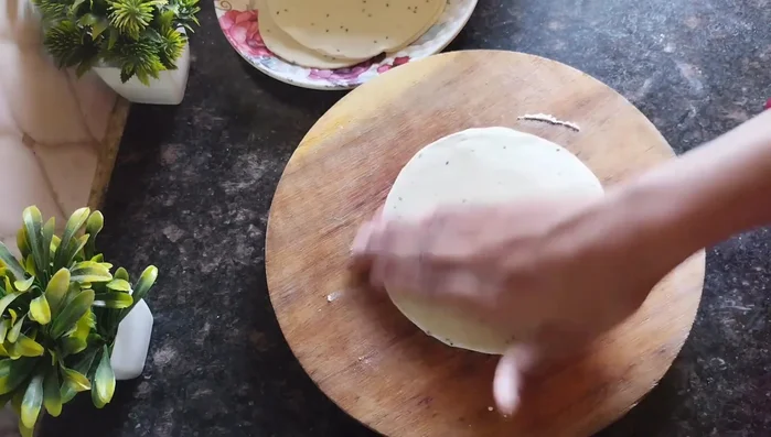 Layer the rolled dough: Place one rolled circle on a clean surface, brush with oil, sprinkle with flour. Repeat this process with more rolled circles layering them on top of each other.
