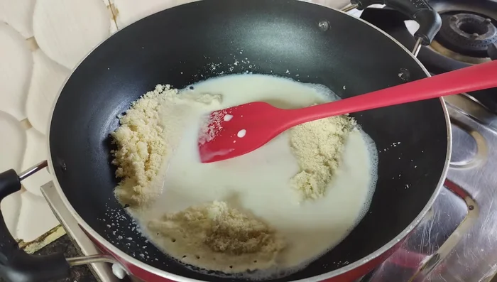 Combine semolina and milk: Add half of the milk to the fried semolina, mixing well. Then add the remaining milk gradually, stirring constantly on low heat to prevent lumps. Continue stirring until the mixture thickens into a dough.