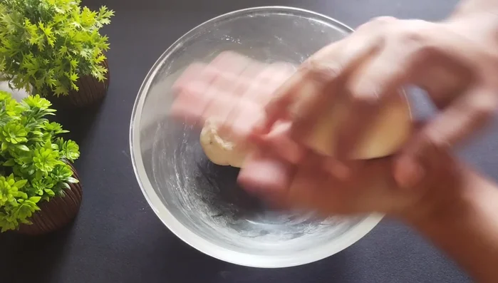 Divide the rested dough into two parts. Roll each part into a thin, medium-thickness circle. Do not add dry flour or oil while rolling.