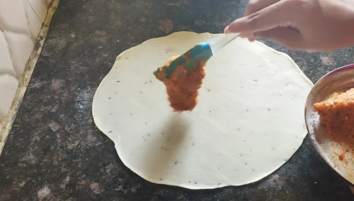 Spread the potato masala evenly over one rolled dough circle. Top with the second rolled circle and seal the edges well. Gently roll it to ensure the filling is evenly distributed.