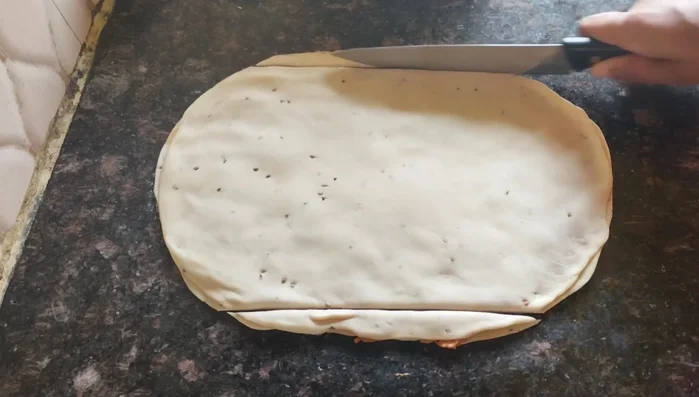 Trim the edges of the dough to create a neat square. Cut the trimmed dough into small pieces for frying.