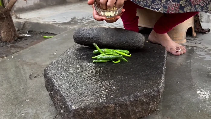 Prepare the green chutney by grinding green chilies, ginger, garlic, and coriander on a grater. Add salt to help grind it finely.