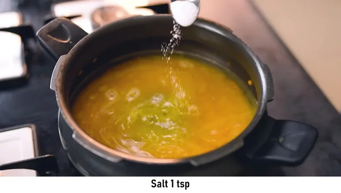 Add water and a bundle of whole spices (cardamom, mace, cinnamon, cloves, black pepper, bay leaves) to the cooked dal in the cooker. Cook until the dal is well-dissolved and pasty (3-4 whistles).