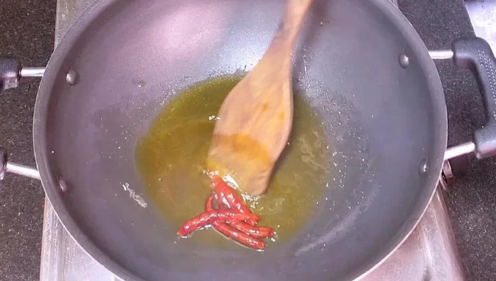 Heat mustard oil in a pan. Add dry chilies (lightly fry and remove).