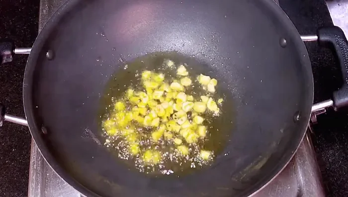 Add black cumin seeds, raw chili, and chopped garlic to the oil and fry.