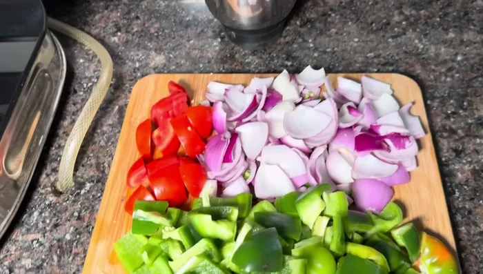 Prepare the gravy base by sautéing onions, tomatoes, capsicum, garlic, and green chilies.