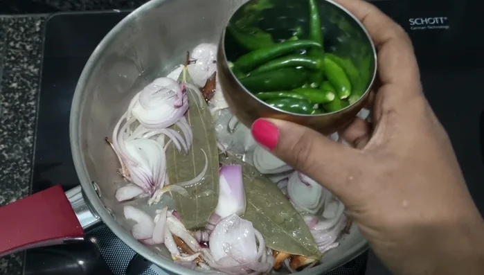 Add green chilies and fry briefly. Then, add chopped tomatoes and fry until a sauce forms.