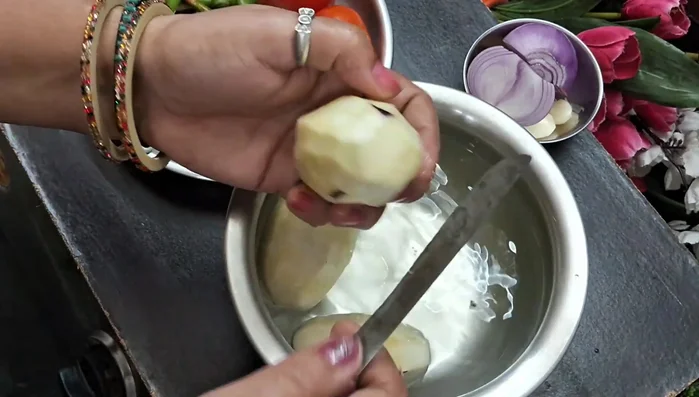 Cut the brinjal, removing the stalk. Peel the brinjal and cut it into small pieces while submerged in water to prevent browning.