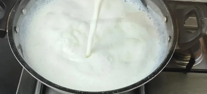 Cook the milk for 7-8 minutes, or until the water content reduces significantly. Stir the milk constantly from bottom to top, creating a thick foam. This helps in achieving a granular texture and creamy curd.