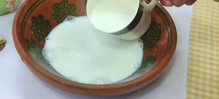 Pour the hot milk into an earthenware, steel, or glass utensil gently, letting it flow from a height to create more foam. This process improves the texture of the curd.