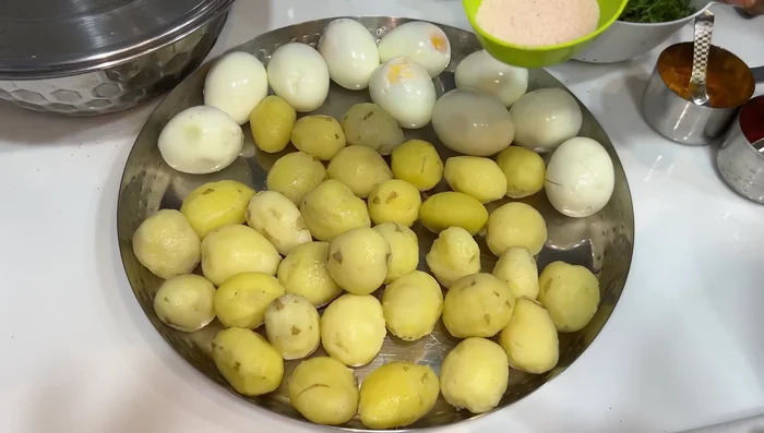 Prepare eggs and potatoes: Cut eggs, add salt, turmeric powder, chili powder, and mustard oil. Fry until golden brown. Similarly, fry the pre-boiled potatoes.