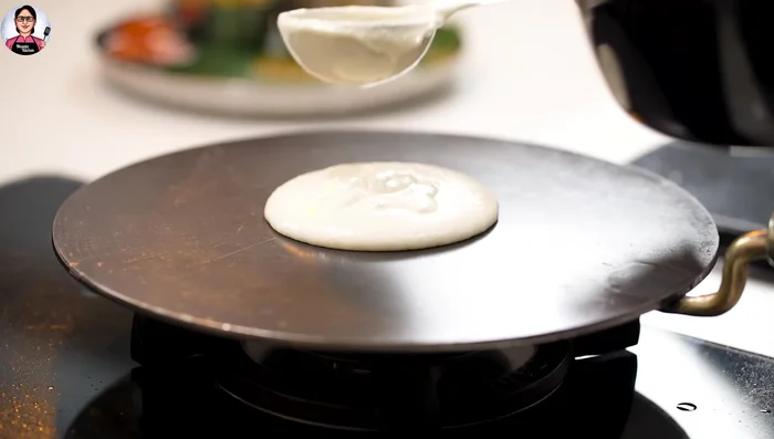 Pour batter: Pour a thick ring of batter onto the hot tawa, reduce the heat to low.