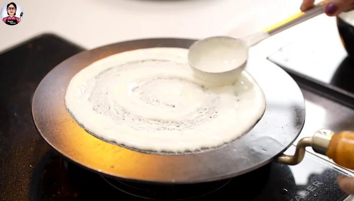 Spread and cook: Spread the batter evenly. Add butter and let it cook until the edges start to lift. Rotate the pan to ensure even cooking.