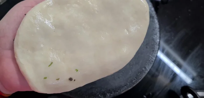 Lightly wet one side of the naan and place it on the hot tawa. Cook until bubbles appear on the surface.