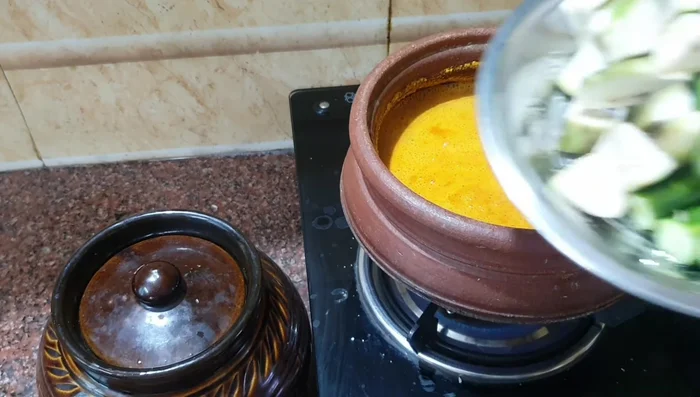 Add the chopped drumstick, eggplant, banana, tomato, chilies, and curry leaves to the gravy. Boil until the vegetables are about 80% cooked.