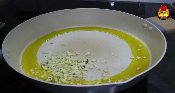 Add the finely chopped garlic and green chilies to the hot oil. Cook together to prevent burning the garlic.