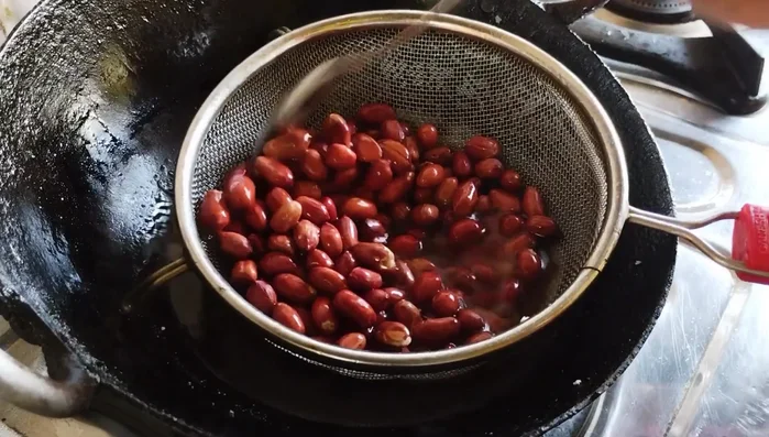 Fry raw peanuts on low flame until crispy and light brown.
