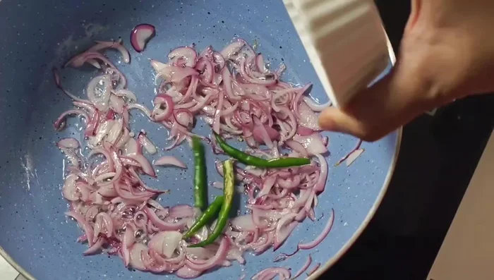 Add slit green chilies and continue sautéing until onions are golden brown.
