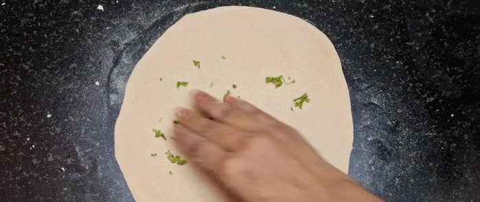 Sprinkle coriander leaves on top of the rolled dough.