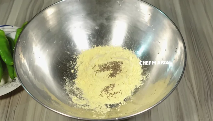 In a bowl, mix gram flour, celery/cumin seeds, red chilli powder, and salt. Gradually add water to make a thin batter, ensuring no lumps form.