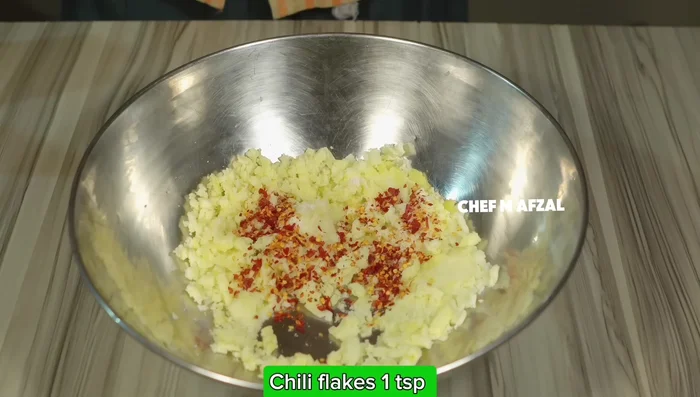 Add salt, crushed red chilli powder, mayonnaise (or ketchup, or both), and crushed cheese to the mashed potatoes. Mix thoroughly.