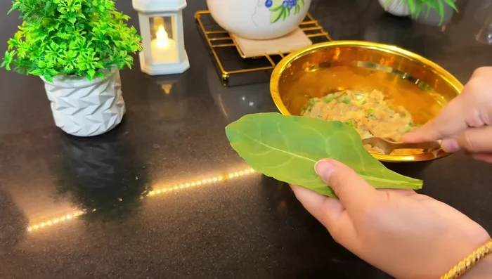 Take a spinach leaf, place a spoonful of potato stuffing in the center, and top with another spinach leaf.
