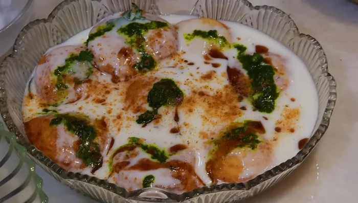 Serve the dahi bhalle by adding yogurt, green chutney, tamarind chutney, and chaat masala.