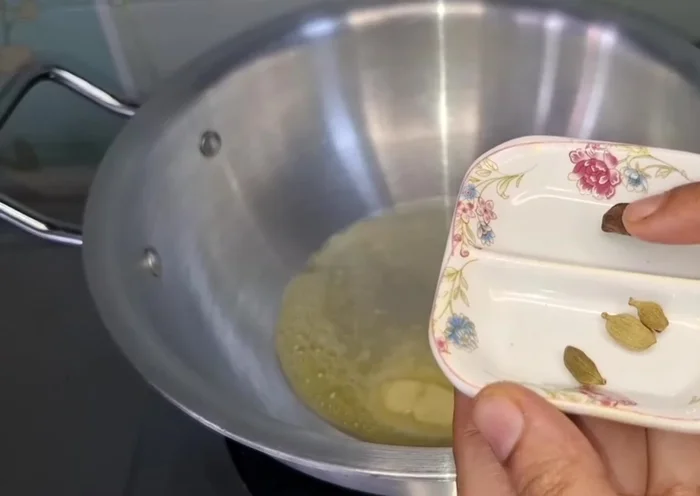 Heat 1.5 tbsp butter and 1.5 tbsp oil in a pan. Add crushed green cardamoms and saute.