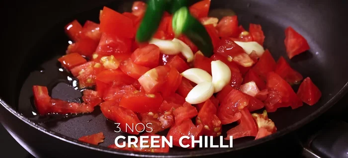 In the same pan, sauté tomatoes, garlic, green chilies, and tamarind with oil until softened. Add salt and turmeric powder; cook until excess moisture evaporates.