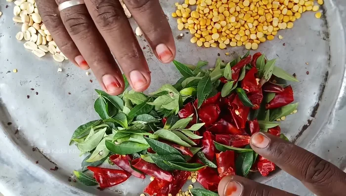 In a pan, heat 300ml of oil. Add mustard seeds, fenugreek, and then the remaining seasoning ingredients (cashew nuts, groundnuts, curry leaves). Fry until fragrant.