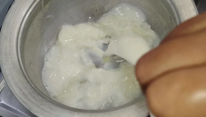 Add about three cups of milk to a vessel, reserving one cup. Add a little water to the vessel.