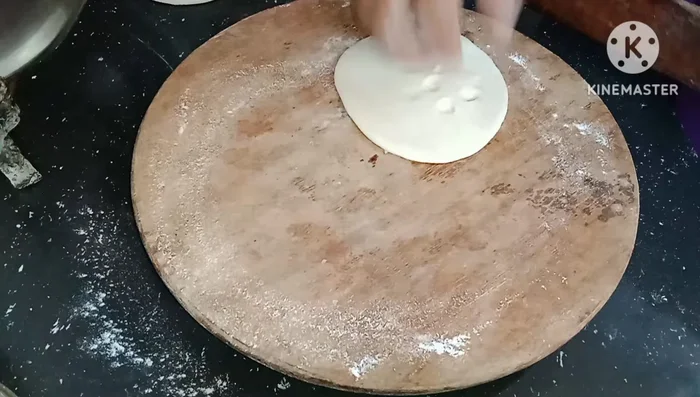 Prepare the roti base: Layer 3-4 puris, applying flour in between, and roll them into large, thin rotis.