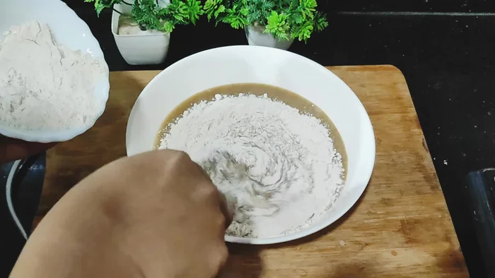 Add 1 cup of wheat flour (or refined flour) gradually to the bowl, mixing well after each addition. Do not add all the flour at once.