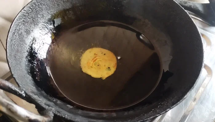 Fry the mathri in hot oil over low heat until golden brown and crispy.