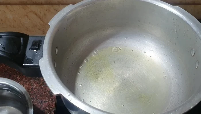 Heat oil and ghee in a cooker. Add mustard seeds, cumin seeds, and fenugreek seeds; let them splutter.