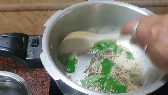Add curry leaves, onions, garlic, and green chilies. Sauté until onions turn translucent.