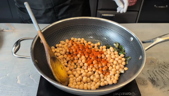 Add 800g of tinned chickpeas, 2 teaspoons of red chili powder, 2 teaspoons of salt, 1 teaspoon of ginger paste, 1 tablespoon of garlic paste, 1 teaspoon of sugar, 1 teaspoon of turmeric powder, and 1 teaspoon of coriander and cumin powder. Mix well for 30 seconds. (46.92)