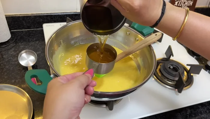 Add half a cup of ghee to the sugar syrup, let it boil and then add the gram flour batter. Cook on slow to medium flame, stirring continuously until the mixture thickens and comes together.