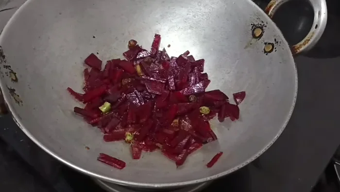 Add the chopped beetroot and leaves to the pan. (Optional: Add onion and dried red chili at this stage or later.)
