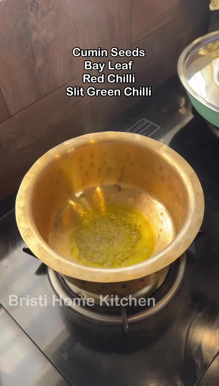 For dal seasoning: Heat mustard oil, add cumin seeds, bay leaves, dried red chilli, green chilli, garlic, and asafoetida (309.919).
