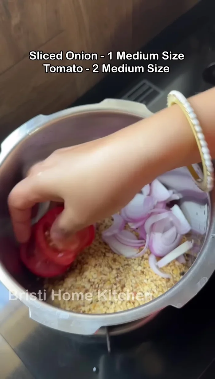 In a cooker, add the washed dal, chopped onion and tomatoes, turmeric powder, salt, and coriander powder (93.56).