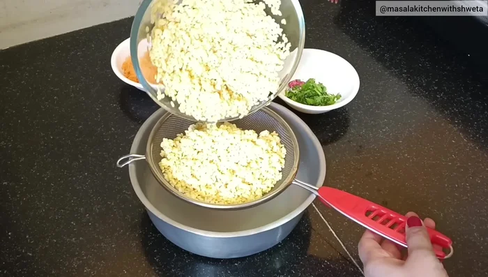 Drain excess water from the soaked moong dal using a sieve.