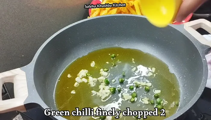 Heat cooking oil in a pan. Add chopped garlic and green chilies and sauté until fragrant.