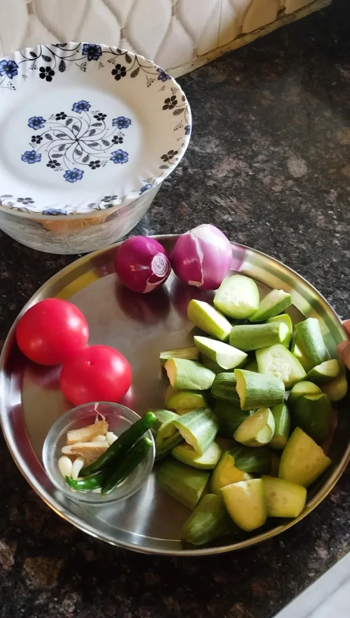 Prepare the potato parwal sabzi: Chop parwal into four parts and wash well. Chop onions, tomatoes, green chilies, ginger, and garlic finely.