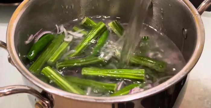 Add 2 cups of water, salt, and a little turmeric powder to the pan. Boil until the drumsticks are soft (10-15 minutes).