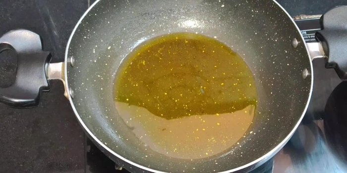 Heat a pan and pour in one tablespoon of mustard oil. Heat until it starts smoking.